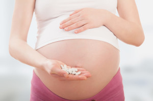 Mulher grávida segurando comprimidos de ácido fólico