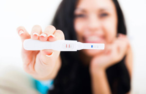 Mulher segurando um teste de gravidez positivo e sorrindo