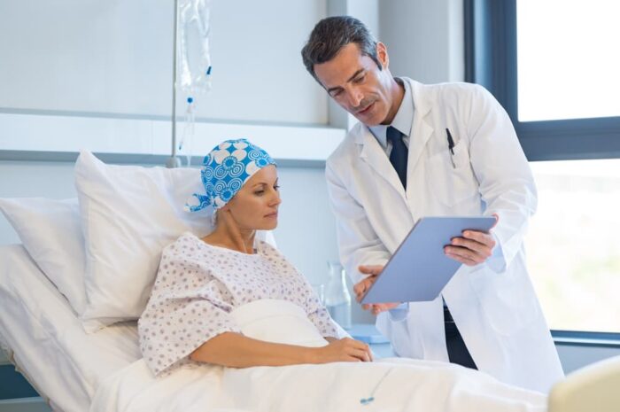 mulher com câncer em cama de hospital durante tratamentos oncológicos recebendo tratamento acompanhada pelo médico