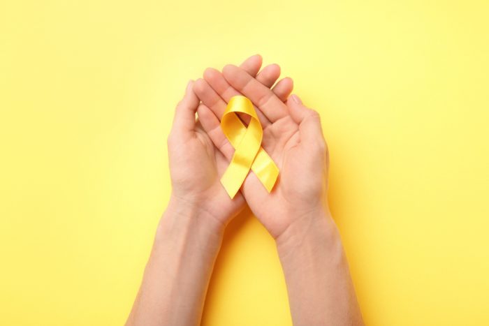 Duas mãos seguram laço amarelo em referência ao mês de conscientização sobre endometriose
