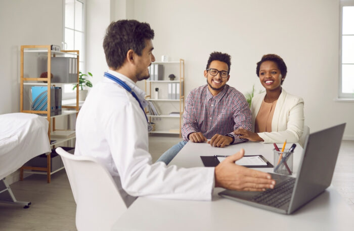 Casal negro em consulta com um médico branco.