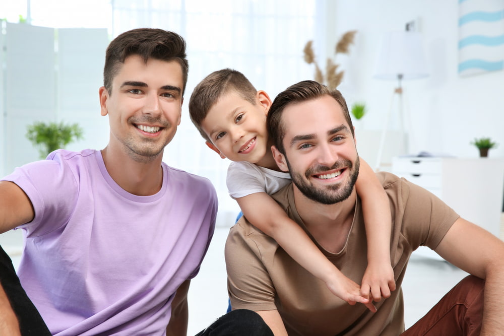 Dois homens e uma criança sorrindo.