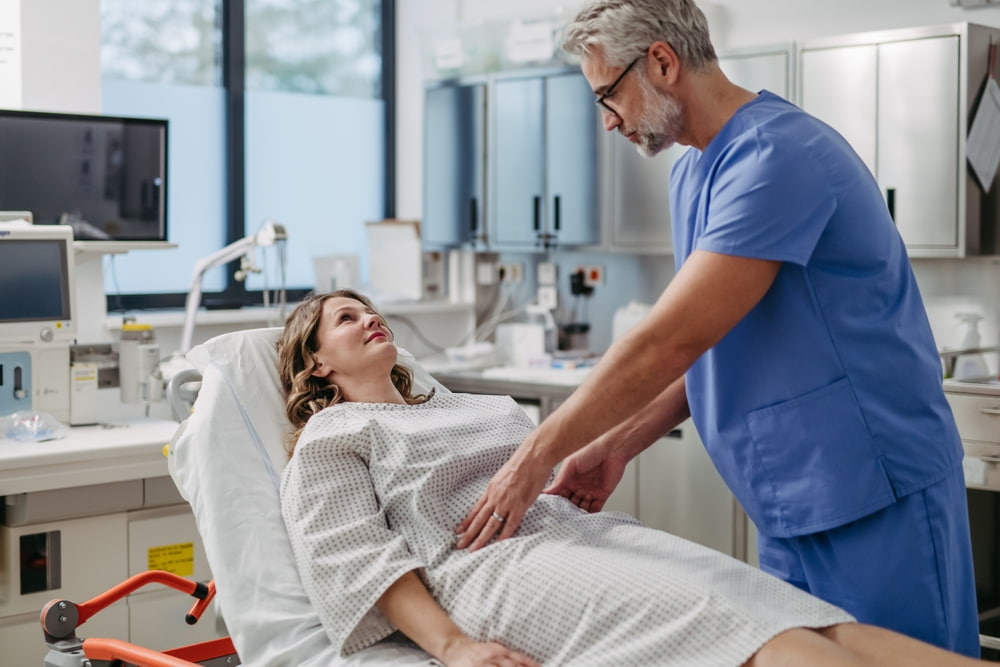 Médico examinando paciente deitada.