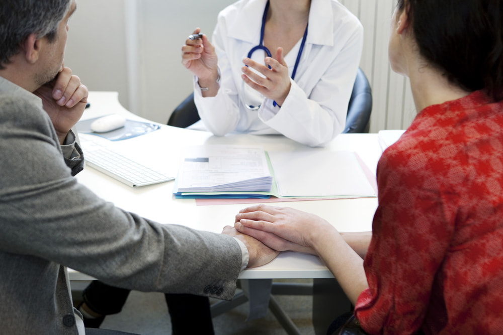 Casal de mãos dadas em consulta médica