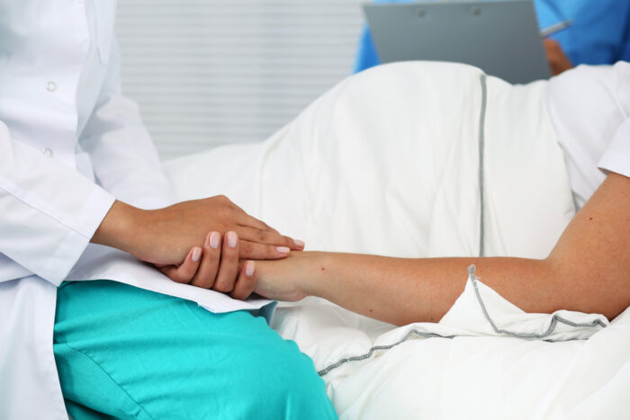 Médica segurando mão de uma paciente.