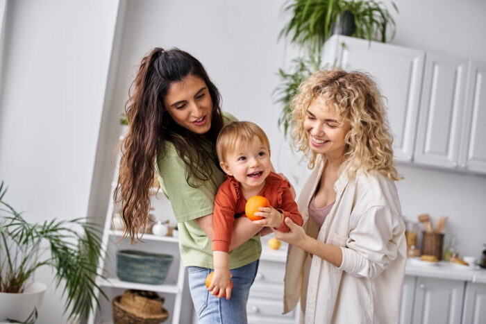 Família homoafetiva feminina brincando com um bebê, possivelmente o filho delas.