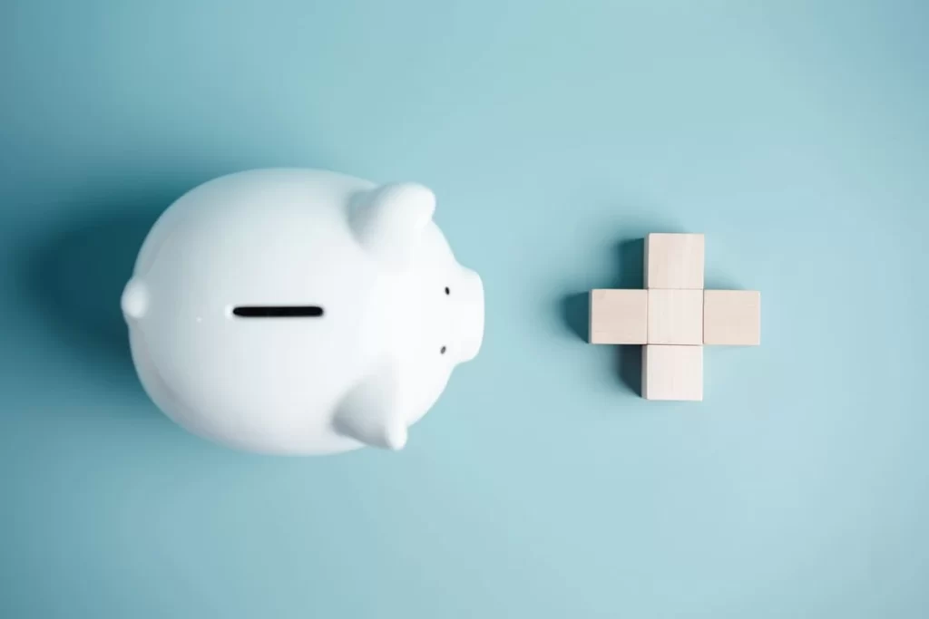 Cofrinho ao lado de cruz médica ilustrando o valor da inseminação artificial.