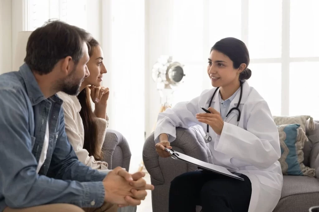 Médica em consulta com casal discutindo quanto tempo esperar entre uma FIV e outra.