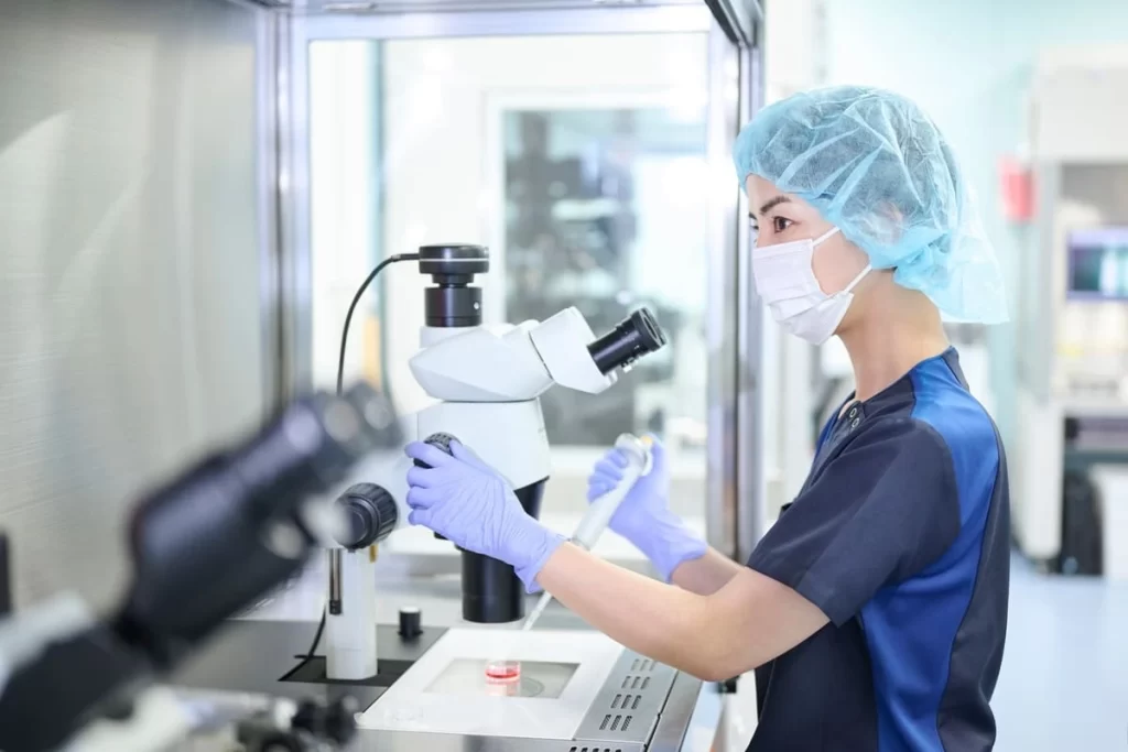 Médica com pipeta e microscópio representando os motivos pelos quais a fertilização in vitro pode falhar.