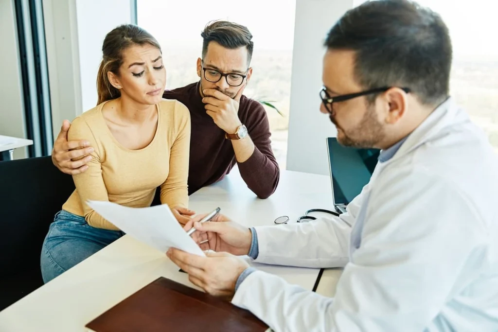 Casal preocupado em consulta médica ilustrando a dúvida se quem não tem útero pode engravidar.